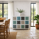 Lifestyle imagination of a carved mango wood chest of drawers with twelve multicolour floral drawer fronts, 124 × 40 × 102 cm.