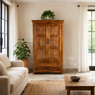 Lifestyle image of a dark brown mango wood cabinet with hand carvings, 2 drawers and ample storage.