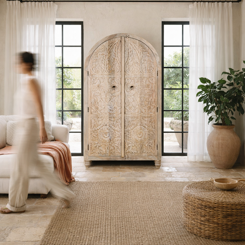 Lifestyle image of a handcrafted mango wood wardrobe with arched top and floral carving – Tamia by Om Home & Garden, unique furniture with Ibiza-style charm for living rooms and bedrooms.