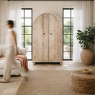 Lifestyle image of a handcrafted mango wood wardrobe with arched top and floral carving – Tamia by Om Home & Garden, unique furniture with Ibiza-style charm for living rooms and bedrooms.