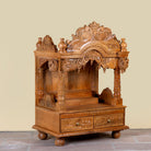 Side angle image of a Meher hand carved mango wood mandir with traditional Indian temple details and two small drawers.