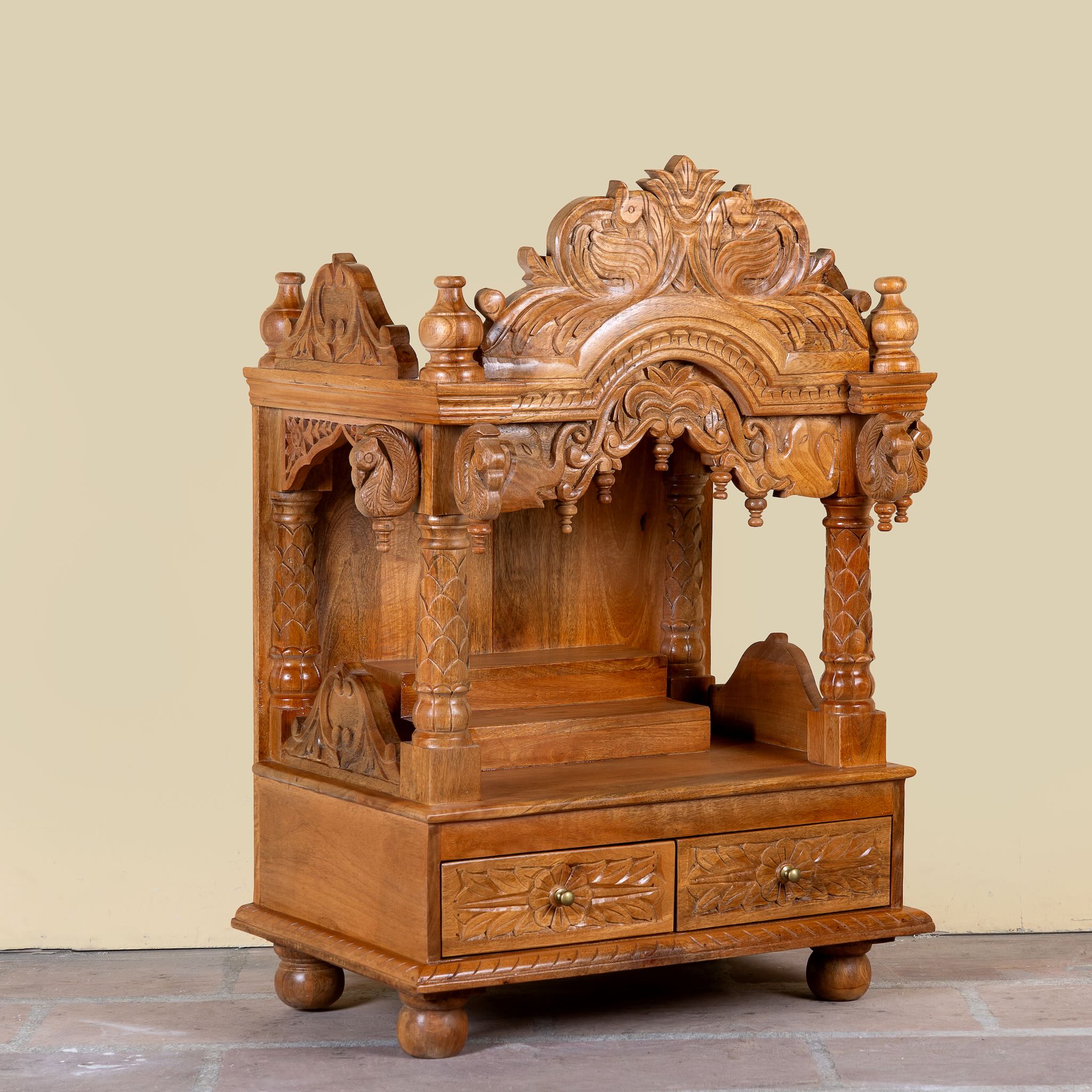Side angle image of a Meher hand carved mango wood mandir with traditional Indian temple details and two small drawers.