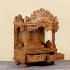 Side angle image with open drawers of a Meher hand carved mango wood mandir with traditional Indian temple details and two small drawers.