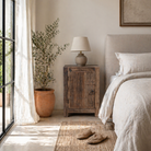 Lifestyle scene with a reclaimed wood bedside table with single cabinet door – handcrafted driftwood furniture ideal for rustic minimalism and natural interior styling.