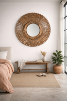 Lifestyle imagination of a of a round mango wood mirror Babra with concentric carved design and mirror inlays. A piece of unique wall decor combining artisanal craftsmanship and rustic bohemian charm.