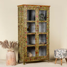 Side angle image of a hand-painted reclaimed wood cabinet with glass doors and floral motifs – sustainable and artistic furniture for vintage or bohemian interiors.