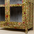 Close up image of a hand-painted reclaimed wood cabinet with glass doors and floral motifs – sustainable and artistic furniture for vintage or bohemian interiors.