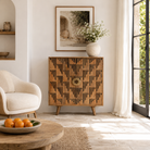 Lifestyle image of a artisanal mango wood cabinet with natural doors, black frame, and brass knobs, 91 × 113 × 41 cm.