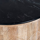 Close up view of a elegant round hand carved coffee table made of sustainable Mango wood with floral design and black marble top.