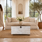 Lifestyle image of a hand carved mango wood chest box with white washed vintage finish and iron lock, 105x70x55 cm