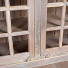 Close up image of a tall reclaimed wood cabinet in sandblasted vintage design with glass-panelled doors; rustic living room furniture, 100 × 40 × 190 cm.