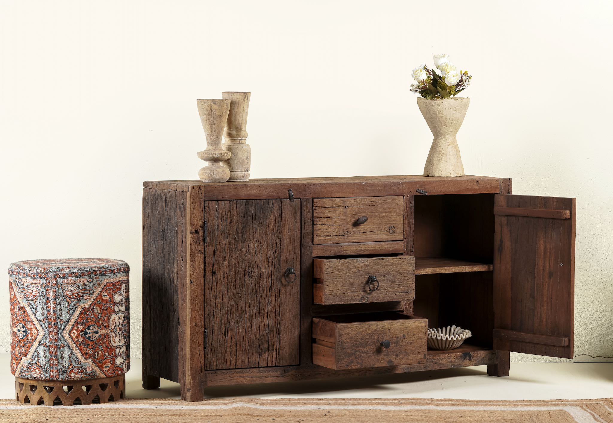 Side angle image with open doors of a storage rustic sideboard made of reclaimed wood with 3 drawers and 2 doors.