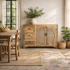 Lifestyle image of a hand carved mango wood cabinet in natural finish with 3 drawers and 2 rattan doors.
