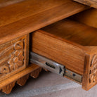 Close up picture of the drawer of a hand carved mango wood Indian mandir temple with ornate floral carvings, lattice doors, and two storage drawers.