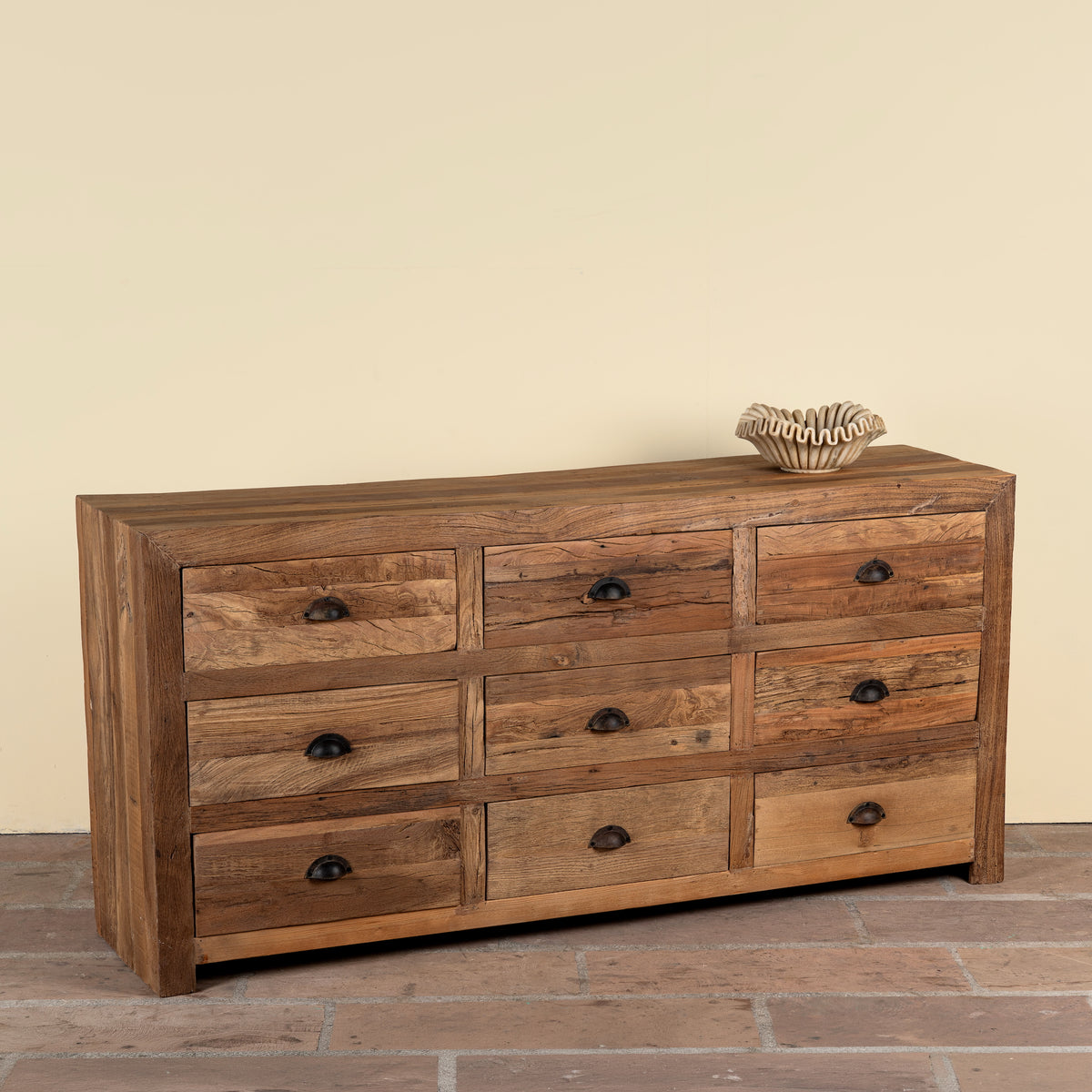 Side angle image of a Nayel reclaimed wood chest of 9 drawers with dark metal cup handles in Japandi style, 180cm
