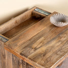 Close up image of a hand carved mango wood nightstand with two drawers and hidden compartment in rustic artisan style.