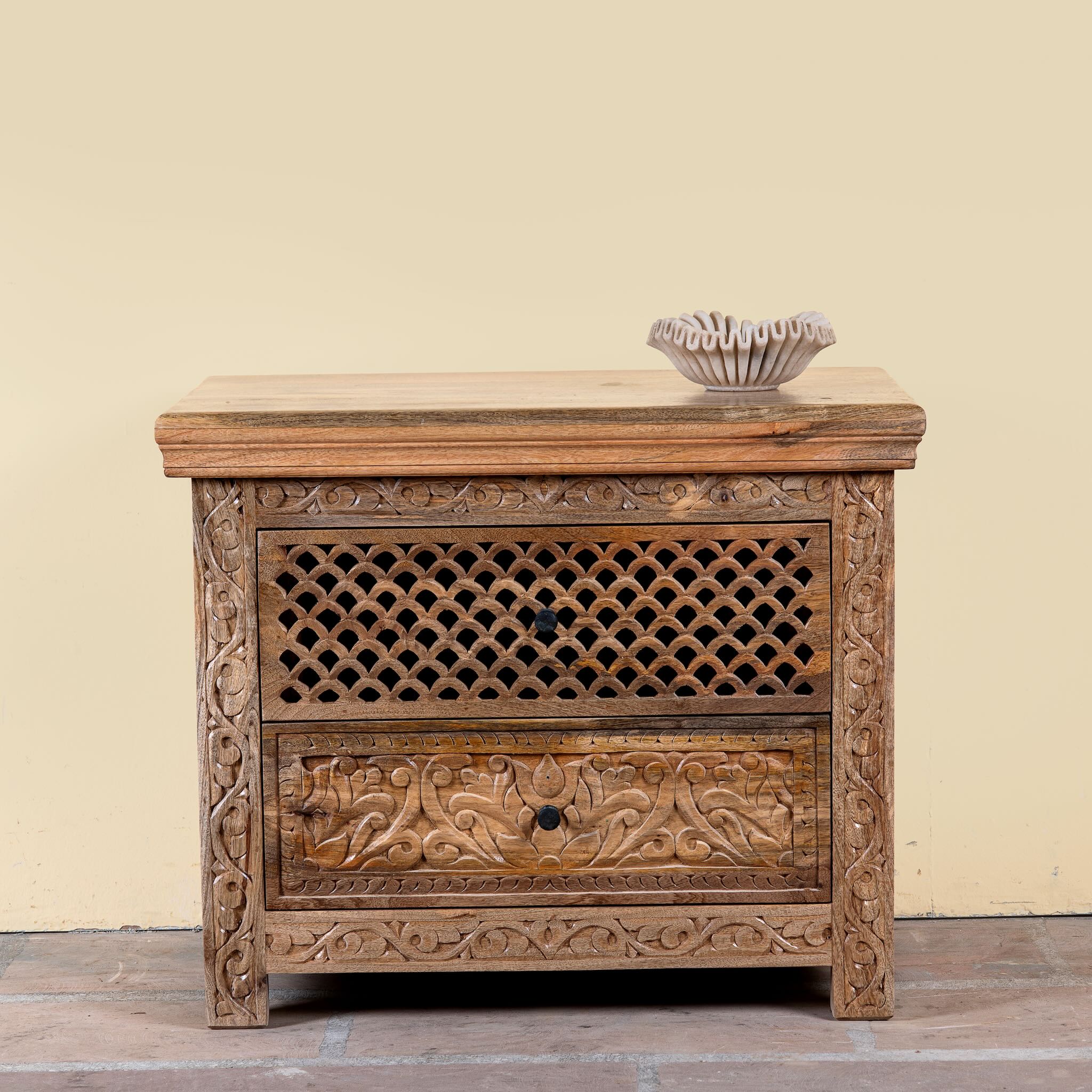 Hand carved mango wood nightstand with two drawers and hidden compartment in rustic artisan style.
