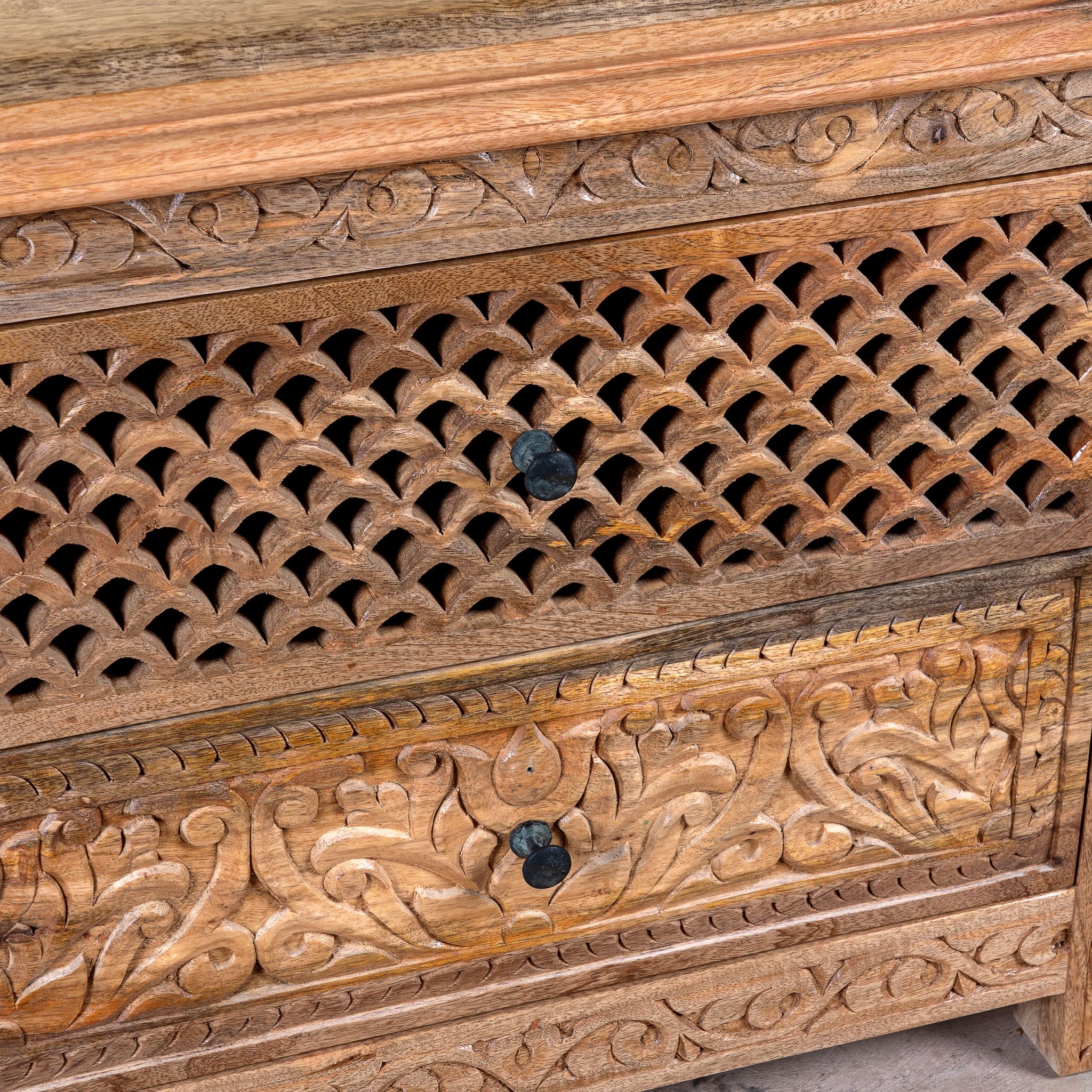 Close up image of a hand carved mango wood nightstand with two drawers and hidden compartment in rustic artisan style.