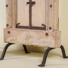 Close up of the iron stand of a mirror stand crafted from reclaimed teak wood with intricate carved detailing and two storage cabinets, set on a sturdy iron base, blending rustic charm with vintage Indian architectural elements.
