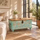 Lifestyle image of a Neysa hand carved mango wood chest coffee table with turquoise floral design, natural wood top and iron lock, 90cm wide