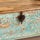 Close up image of a Neysa hand carved mango wood chest coffee table with turquoise floral design, natural wood top and iron lock, 90cm wide