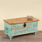 Side angle image of a Neysa hand carved mango wood chest coffee table with turquoise floral design, natural wood top and iron lock, 90cm wide