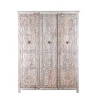 White background image of a large hand carved mango wood wardrobe with floral carvings, whitewashed finish, four doors, and drawer storage.