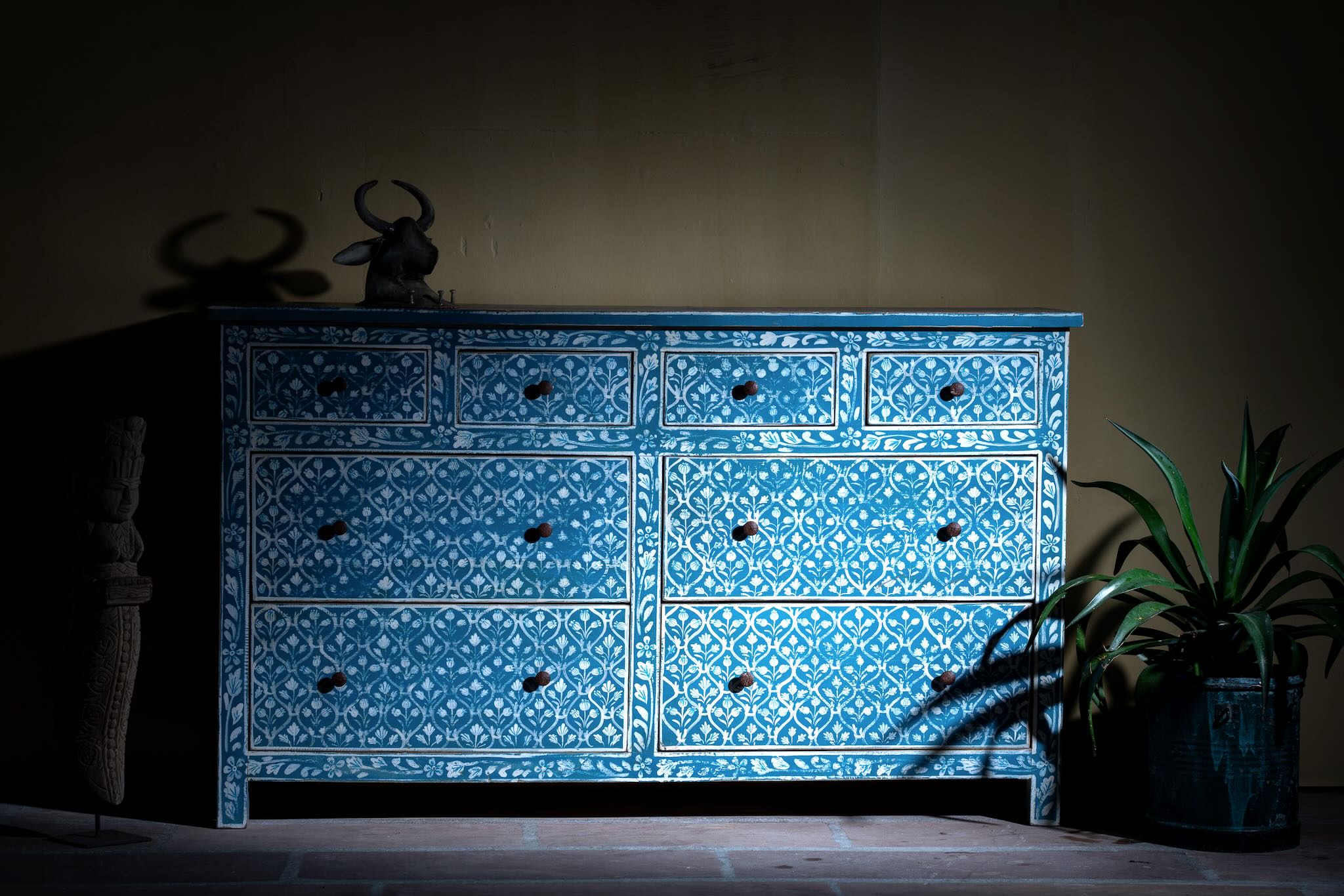Lifestyle image of a hand-painted chest of drawers made of reclaimed wood in blue and white – Nitara model by Om Home & Garden