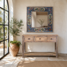Lifestyle image of a Nithya hand-painted reclaimed wood wall mirror featuring colourful peacocks, birds and floral Indian artwork, 90x90x5cm.