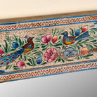 Close up image of a Nithya hand-painted reclaimed wood wall mirror featuring colourful peacocks, birds and floral Indian artwork, 90x90x5cm.