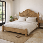 Lifestyle image of a mango wood bed frame with hand carved headboard in vintage style.