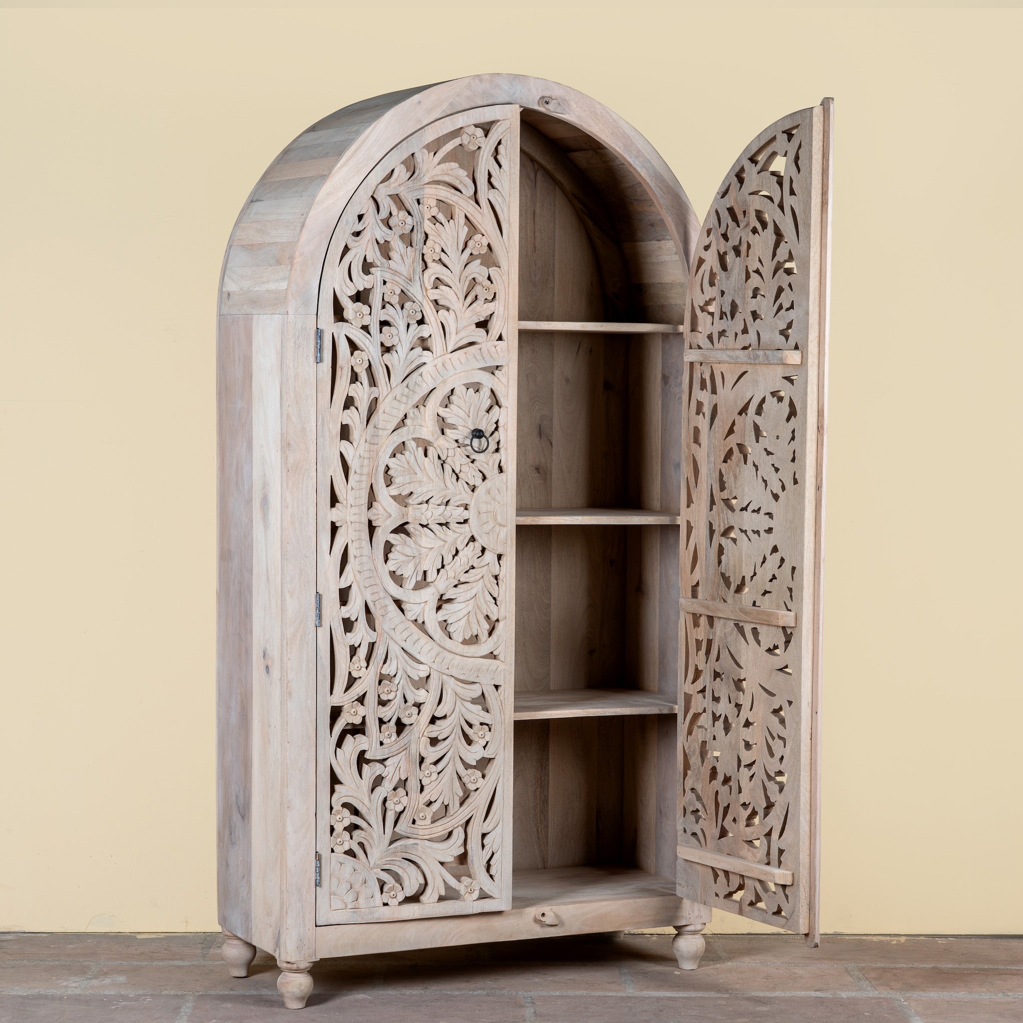 Side angle image with open doors of a  hand-carved mango wood wardrobe, a statement piece of bedroom furniture ideal for a bohemian interior.