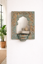 Lifestyle imagination of a hand-carved wooden mirror with candle holder in distressed turquoise finish, featuring Indian arch design – ideal for vintage and Indian home accessories.