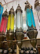 Decorative glass lanterns with colorful panels hanging on a rack.