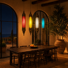 Ovin oriental pendant light crafted from hand-punched metal and coloured Belgium glass, featuring a tall hexagonal lantern design with multicoloured glass panels and intricate decorative shadow patterns, 100cm.
