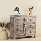 Side angle image of a handcrafted cupboard made from reclaimed wood with a carved turtle motif and pastel finish; vintage furniture and sustainable furniture, 110 × 96 × 40 cm.