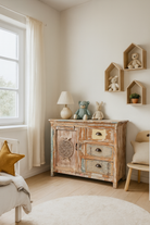 Lifestyle image of a handcrafted cupboard made from reclaimed wood with a carved turtle motif and pastel finish; vintage furniture and sustainable furniture, 110 × 96 × 40 cm.