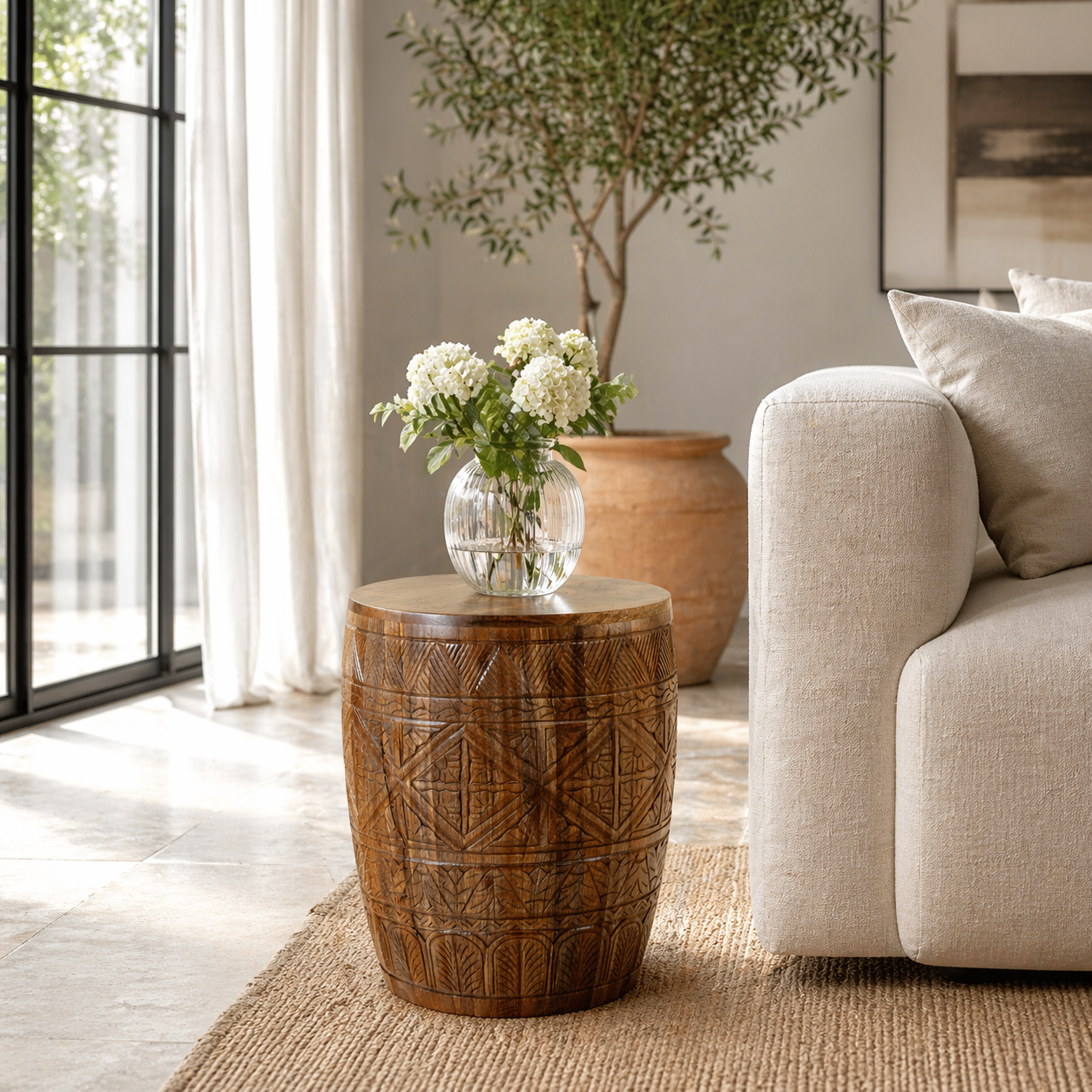 Lifestyle image of a round mango wood side table with hand carved floral and geometrical design.