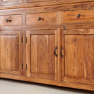 Close up image of a two-part showcase cabinet made from reclaimed teak wood, featuring glass-panel upper doors for display, four drawers for storage, and lower cabinets with solid wood doors in a natural finish.