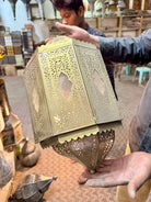 Hand-stamped iron wall lamp Prisha with intricate perforated patterns and antique brass finish, a vintage iron lamp creating warm ambient lighting.