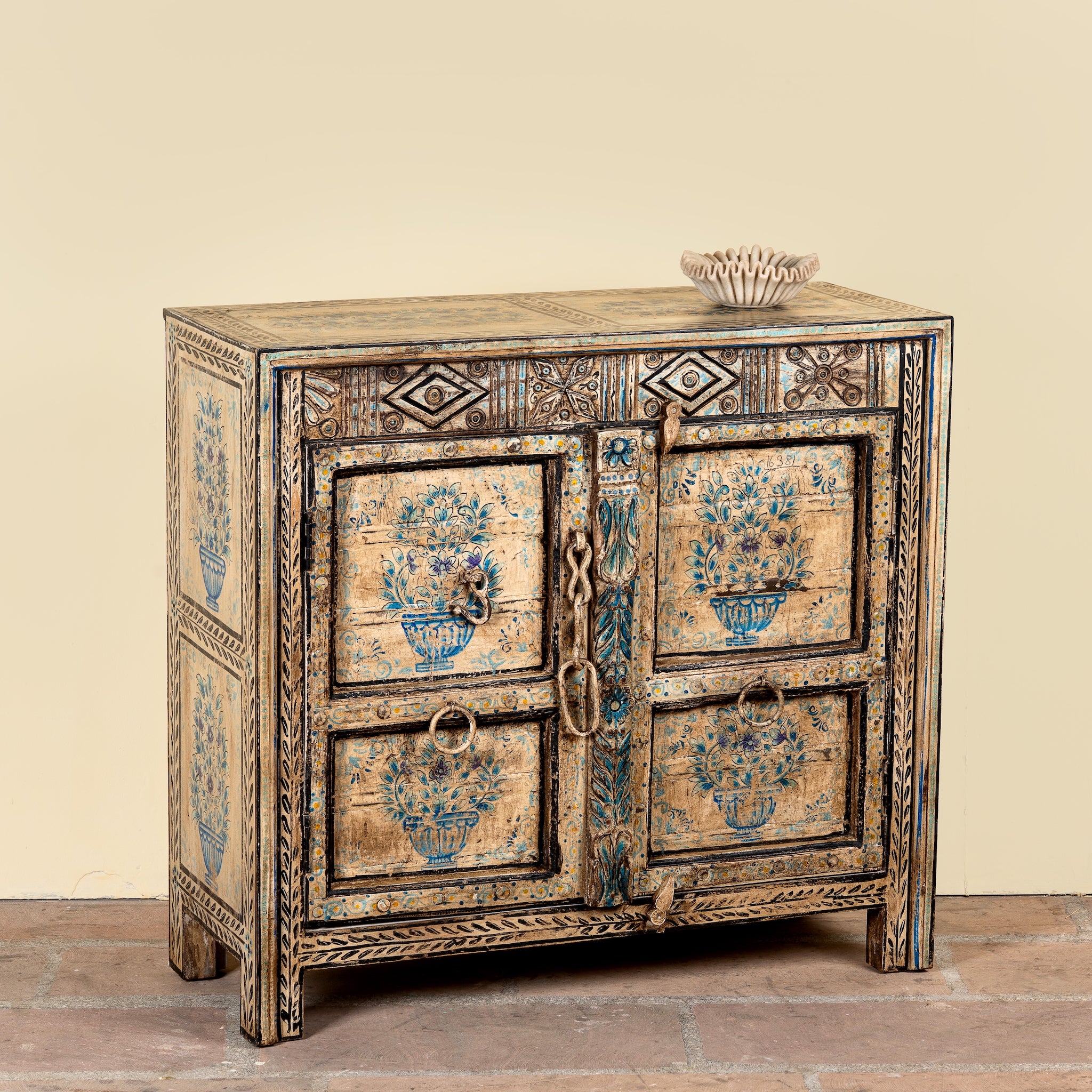 Side angle image of a Prithvi reclaimed wood cabinet with original Indian doors and hand-painted blue and white floral design.