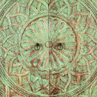 Close up image of a carved mango wood cabinet with floral hand-carving, distressed green finish, iron stand, 100 × 40 × 150 cm.