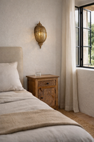 Lifestyle imagination of a antique-style hand-stamped iron wall lamp with brass finish, featuring intricate perforated detailing and vintage ornamental shape.