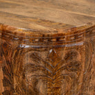 Close up picture of a round mango wood side table with hand carved floral design.