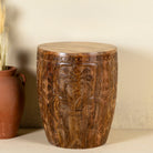 Front view of a round mango wood side table with hand carved floral design.