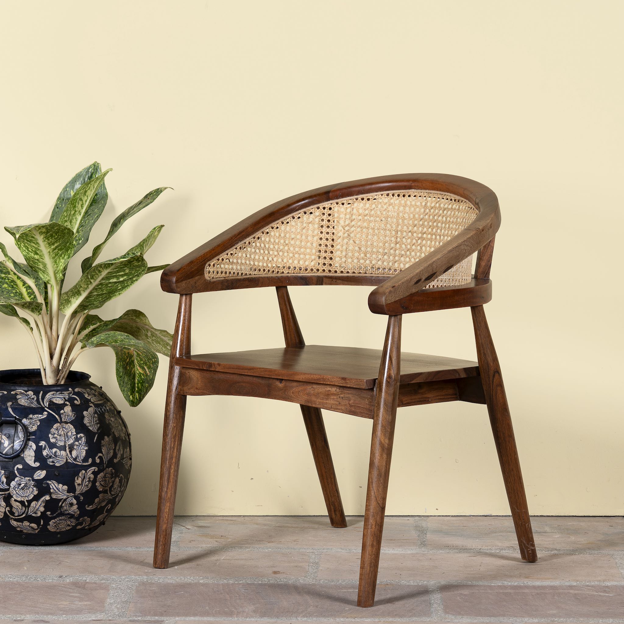 Side angle image of an acacia wood chair with curved frame and woven rattan backrest, elegant wooden armchair, 60 × 45 × 90 cm.