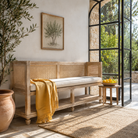 Lifestyle image of a Raipur mango wood bench with handwoven rattan backrest and cotton cushion, 180cm