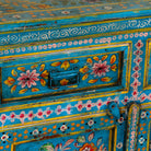 Close up image of a Rajat hand-painted blue reclaimed wood cabinet with colourful floral and animal motifs, two drawers and two doors.