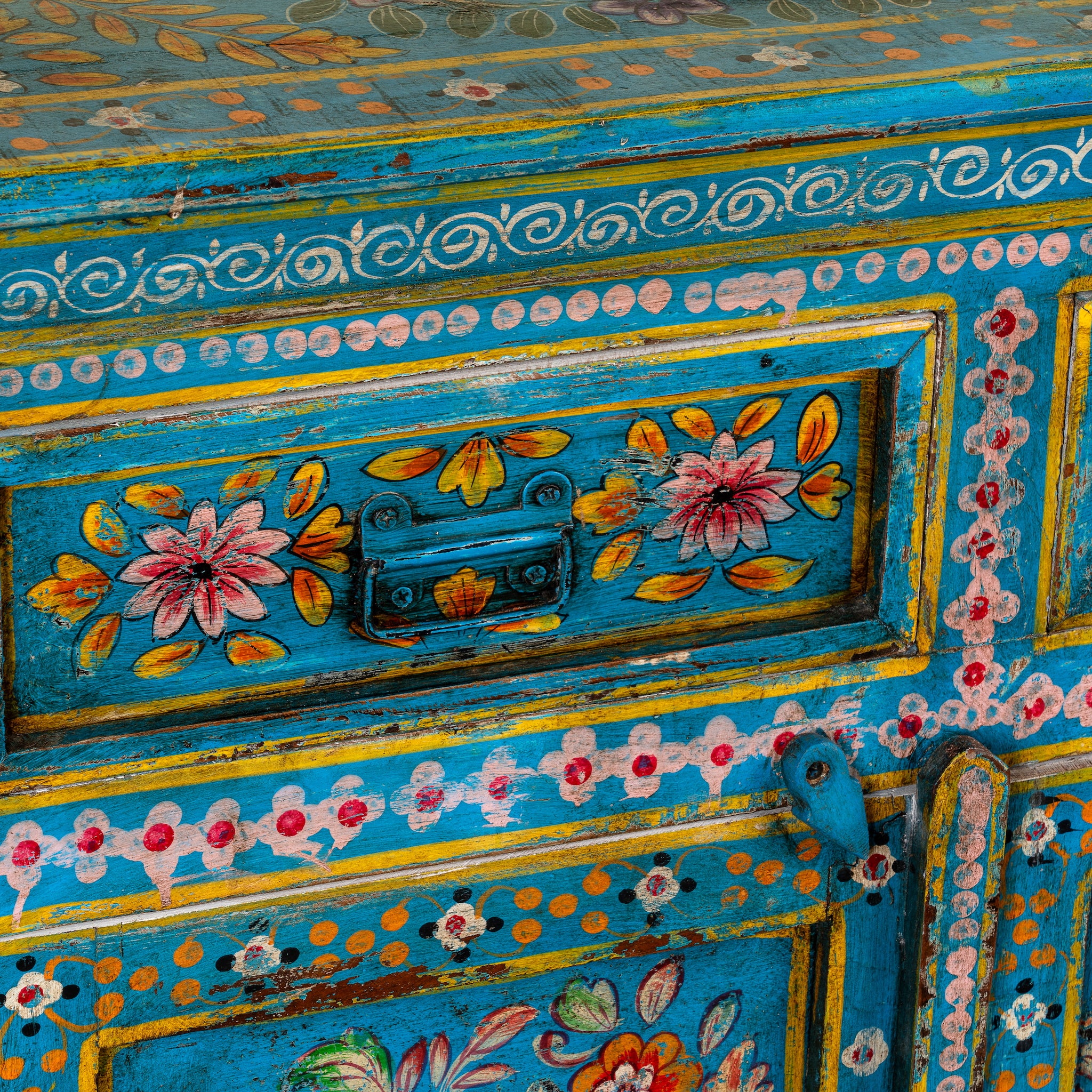 Close up image of a Rajat hand-painted blue reclaimed wood cabinet with colourful floral and animal motifs, two drawers and two doors.