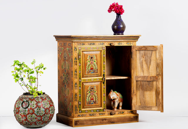 Side angle image with open door of a hand painted reclaimed wood cabinet with floral design in vintage style.